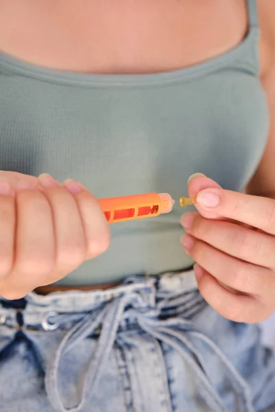 Close-up of a girl using an insulin pen to inject insulin at home. Lifestyle of a child with diabetes. Vertical