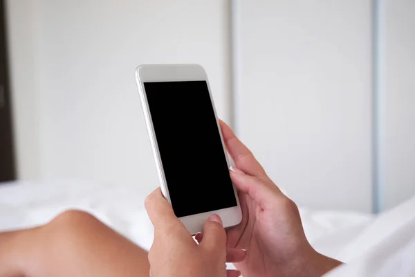 Close-up of phone screen mockup. The girl uses the phone while lying in the bedroom on the bed in the morning.