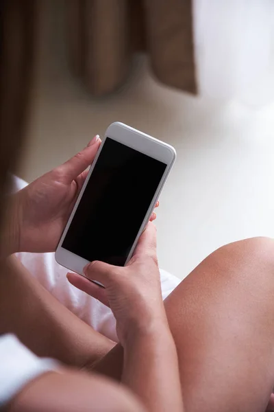Close up smartphone screen template. Young woman holding a smartphone while sitting on the bed in the bedroom. Mockup