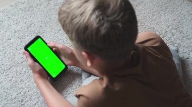 Pre teenager boy browsing content on smartphone. The child scrolls the tape on the Internet. Close up of phone screen with chroma key. Mockup