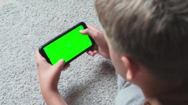 Akıllı telefon tutan bir gencin kafasının ve ellerinin yakın çekimi. Krom anahtarlı cep telefonu ekranı. Uygulama veya içerik için model.
