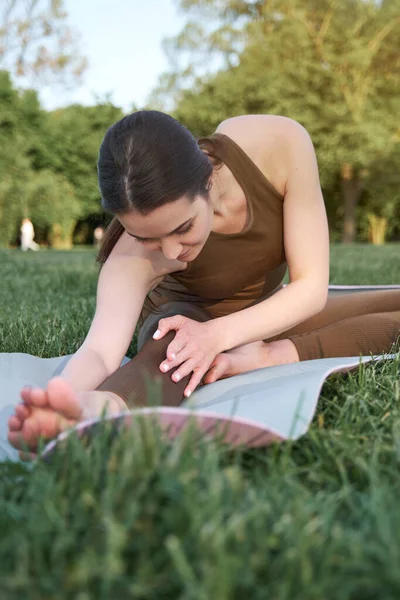 A young woman with a slim figure and long hair goes in for sports in the park on a warm summer day. The concept of a healthy lifestyle.