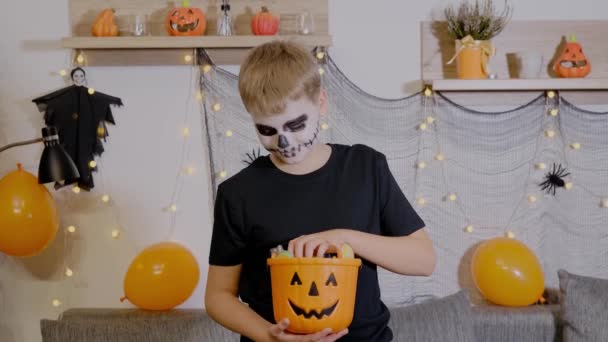 Ένα Αγόρι Μακιγιάζ Σκελετού Κρατάει Ένα Κουβά Καραμέλες Παιδί Γιορτάζει — Αρχείο Βίντεο