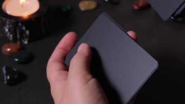 Siyah bir deste kağıt karıştıran bir kadının yakın çekimi. Tarot kartlarının yardımıyla ezoterikizm ve geleceği tahmin etmek