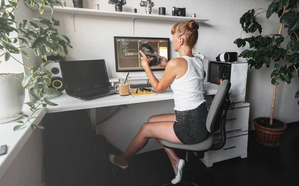 现代开发人员工作场所的女程序员，她们用白色计算机桌面和舒适的扶手椅编写代码. 图库图片