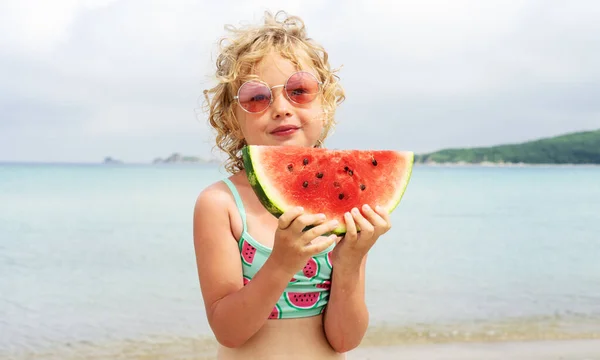 Retrato niña lamiendo rodaja de sandía fresca posando en la playa teniendo diversión y emoción positiva — Foto de Stock