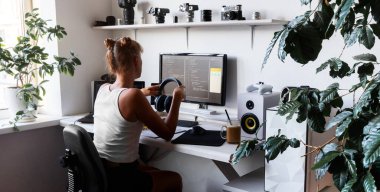 Beyaz bilgisayar masaüstü ve rahat koltuk ile kod yazmak için modern geliştirici iş yerinde kız programcı.