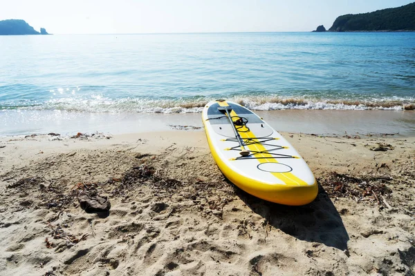 Lege zee landschap zee zand strand met supboard aan de kust kalme golf water oppervlak Stockfoto