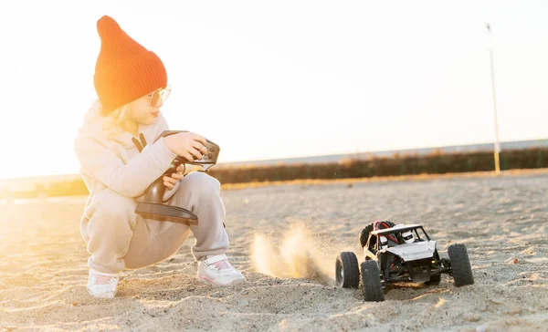 赤ちゃんの女の子は、道路バギー車のおもちゃの無線コントローラをオフに速度レースrc車を再生リモート運転 — ストック写真