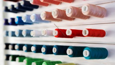 Çok renkli ipliklerin makaralarıyla büyük beyaz standı.