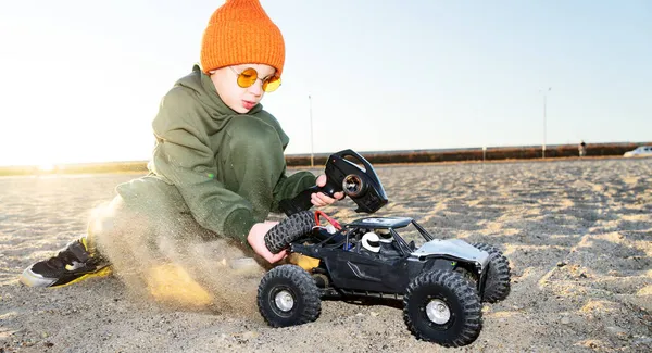 Jongen kind spelen radio control auto rijden op zand outdoor genieten van gelukkige jeugd — Stockfoto