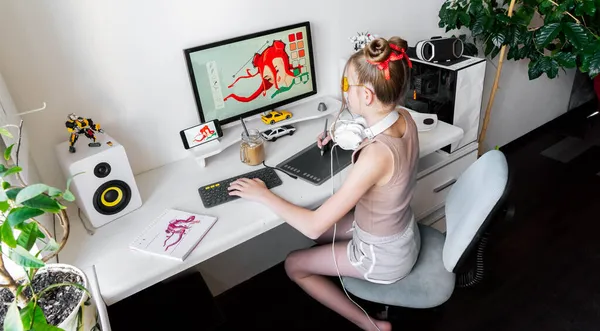 若い女の子は彼女の快適な自宅のオフィスでグラフィックタブレットを使用してPC上で描画します. — ストック写真