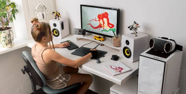 一个年轻的女孩在舒适的办公室里用图形片在电脑上画画. — 图库照片