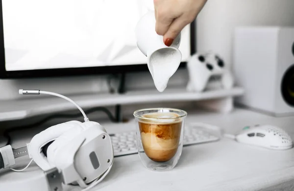 Transparent mug of hot coffee with cream on a white workplace of a programmer and gamer. — Stock Photo, Image