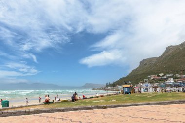 CAPE TOWN,  SOUTH AFRICA - DEC 23, 2021: A beach scene at Muizenberg in Cape Town, Western Cape Province of South Africa. Buildings and people are visible