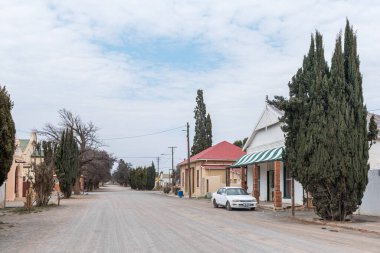 HANover, Güney Afrika - 2. Sezon 2022: Kuzey Burnu, Karoo 'da Hanover' de binalar, bir araç ve ağaçlarla dolu çakıllı bir sokak sahnesi