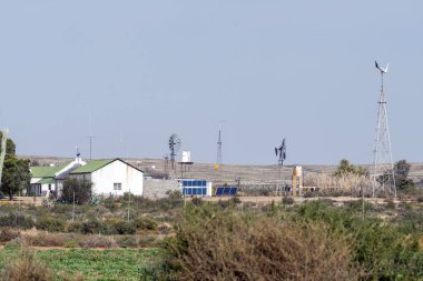 LOXTON, Güney Afrika - SEP 2, 2022: Kuzey Karoo Burnu 'ndaki Loxton yakınlarında bir çiftlikte güneş ve rüzgar enerjisi üretimi. Bir ev ve yel değirmenleri görünür.