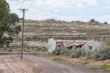 LOXTON, GÜNEY AFRİKA - 2. SEP 2022 Kuzey Karoo Burnu 'ndaki Loxton' da bir evin ve bir elektrik hattının harabesi olan çakıl taşı sokak sahnesi