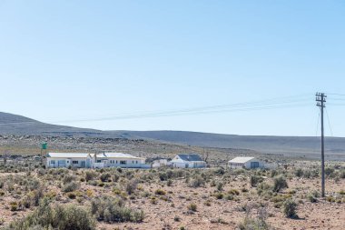 SUTHERLAND, Güney Afrika - SEP 3, 2022: Kuzey Burnu 'ndaki Fraserburg ve Sutherland arasındaki R356 yolu üzerindeki Kuilenburg çiftliğindeki binalar. Açık bir telefon hattı görünüyor