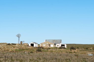 SUTHERLAND, Güney Afrika - SEP 4, 2022: Yel değirmenleri, Kuzey Cape Eyaleti yakınlarındaki Bo-Visrivier yolu üzerindeki Hottentotsfontein çiftliğinde ahır ve ev