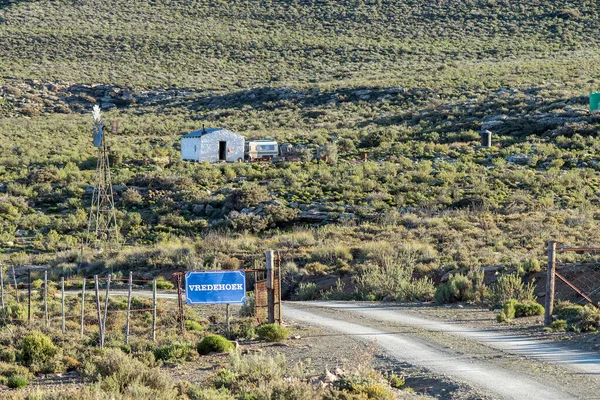 SUTHERLAND, Güney Afrika - SEP 4, 2022: Kuzey Cape Eyaleti 'nin Sutherland yakınlarındaki Bo-Visrivier yolundaki Vadhoek çiftliğine giriş. Bir yel değirmeni, karavan ve çiftlik evi görülebilir.
