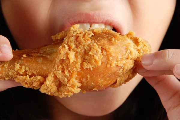A girl tasted fried chicken drumstick