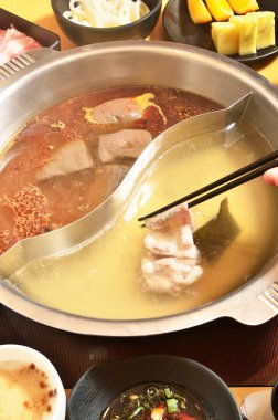 Chopstic sıcak tencerenin üzerinde çiğ et tutuyor.  