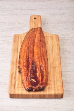 Ahşap kesme tahtasının üzerinde ızgara yılan balığı.