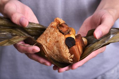 Bambu ya da kamış yapraklarına sarılı zongzi (pirinç köftesi) ile el ele tutuşmak.