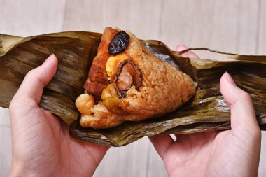 Bambu ya da kamış yapraklarına sarılı zongzi (pirinç köftesi) ile el ele tutuşmak.