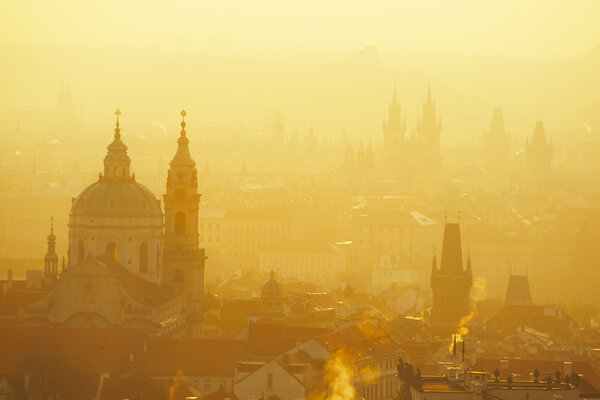 Morning sun over the tops of the towers and houses of Prague.