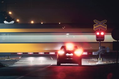 Gece demiryolu. Yolcu treni demiryolu geçidinden geçerken kırmızı uyarı ışıkları durdu.