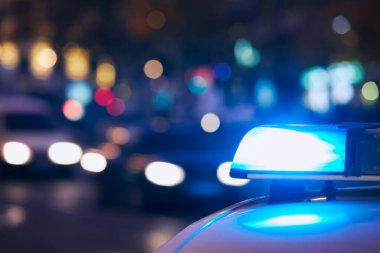 Gece şehir caddesinde polis arabasının sireninin mavi ışığı. Temalar suç, acil durum ve yardım. 