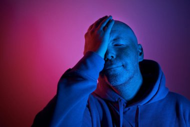 Neon ışıklarının aydınlatıldığı bir portre. Mor ve mavi ışıklı orta yaşlı adam.