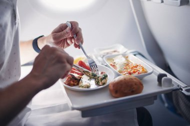 Uçakta havayolu yemeği yiyen yolcu. Orta büyüklükteki taşımacılık uçuşunda business class menüsü.