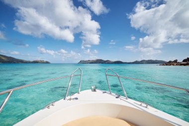 Güneşli bir günde, tropik adalar arasında turkuaz suyla denizde bir geminin pruvası. Praslin Adası, Seychelle
