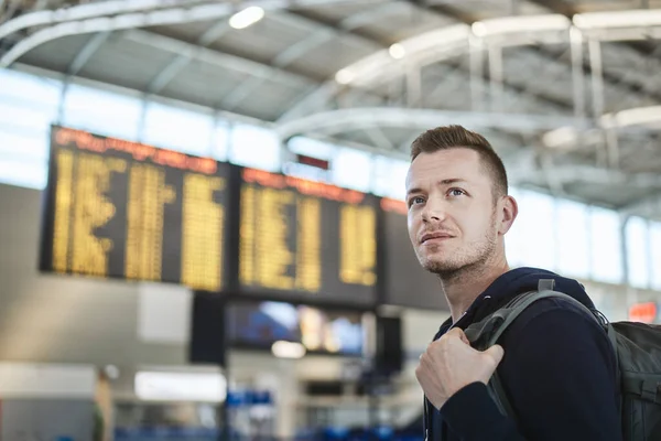 空港でバックパックをしてる男 到着と出発ボードに対する観光客の肖像 — ストック写真