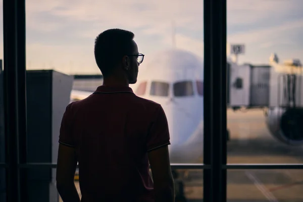 飛行を待っている間の男のシルエット 飛行機に乗る前に空港ターミナルの窓から見る旅行者 — ストック写真
