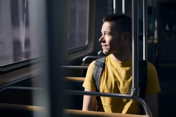 電車の窓の外を見ている孤独な男 晴れた日に公共交通機関でソロ旅行者 — ストック写真