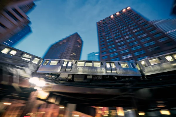 Elevated train in Chicago in blurred motion against skyscrapers in downtown disctrict at night