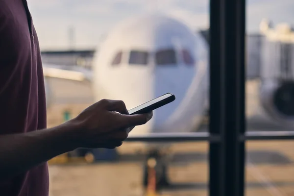空港ターミナルで待っている間に携帯電話を使用している間の乗客の手のシルエット — ストック写真