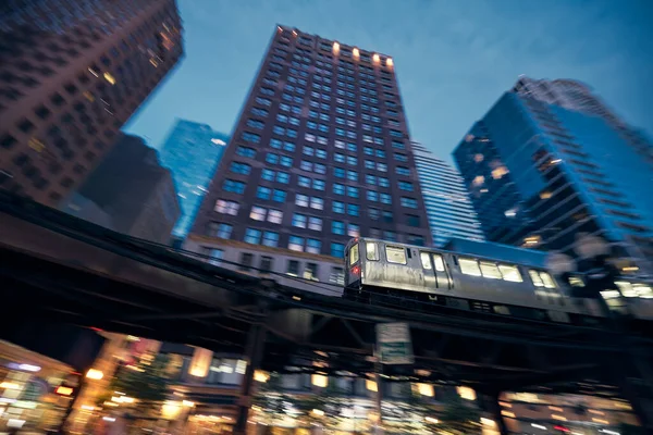 Elevated train in Chicago in blurred motion against skyscrapers in downtown disctrict at night