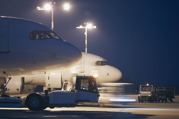 Busy airport at night. Preparation of airplanes before flight.