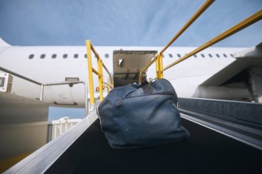 Loading of luggage to airplane. Blue bag on conveyor belt at airport