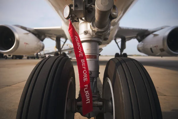 Aircraft nose wheel with red flag Remove Before Flight. Selective focus on airplane at airport