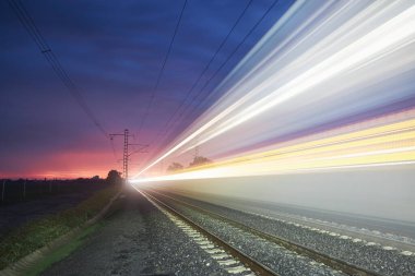 Gündoğumunda modern demiryolu. Tren raylarında yüksek hızlı trenin hafif izleri. Hareket eden modern şehirlerarası yolcu treni
