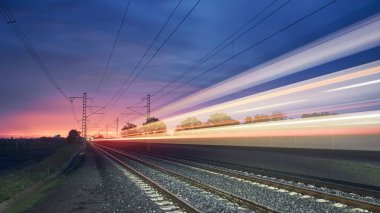 Gündoğumunda modern demiryolu. Tren raylarında yüksek hızlı trenin hafif izleri. Hareket eden modern şehirlerarası yolcu treni