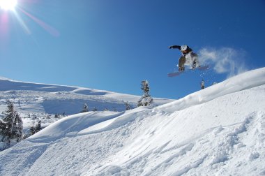 Güneşli bir kış gününde snowboardcu iş başında.