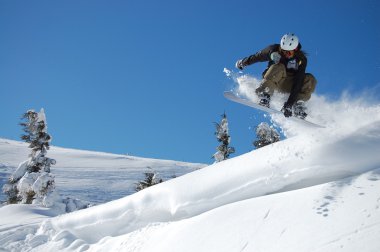 Güneşli bir kış gününde snowboardcu iş başında.