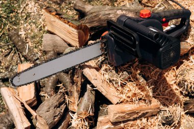 Elektrikli testere yakın çekim. Bir aletle testere. Yakacak odunun arka planında elektrikli testere